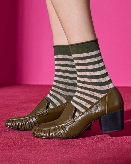 Striped khaki green and beige socks with brown shoes on a pink background