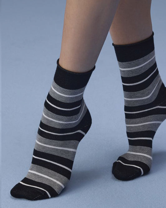 A pair of crew socks with horizontal black, gray, and white stripes, shown on a person's feet against a solid light blue background.